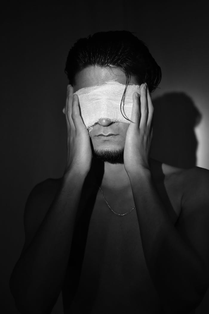 Artistic black and white portrait of man with covered eyes conveying emotion.